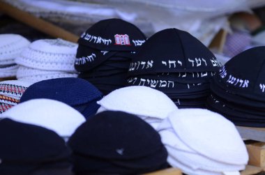 Geleneksel siyah Yahudi kipa kazıkları. Kippah 'ın sözleri pazarda satılmak için dua ediyor. Tanrı bizim Tanrımızdır, Tanrı tektir.