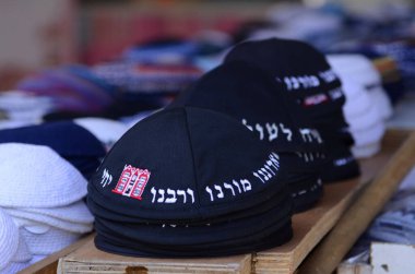 Geleneksel siyah Yahudi kipa kazıkları. Kippah 'ın sözleri pazarda satılmak için dua ediyor. Tanrı bizim Tanrımızdır, Tanrı tektir.