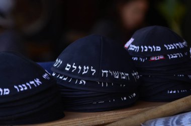 Geleneksel siyah Yahudi kipa kazıkları. Kippah 'ın sözleri pazarda satılmak için dua ediyor. Tanrı bizim Tanrımızdır, Tanrı tektir.