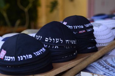Geleneksel siyah Yahudi kipa kazıkları. Kippah 'ın sözleri pazarda satılmak için dua ediyor. Tanrı bizim Tanrımızdır, Tanrı tektir.