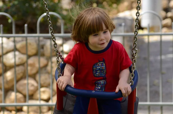 Küçük şirin çocuk parkta salıncakta sallanıyor. Çocuk gülüyor. yakın plan portre