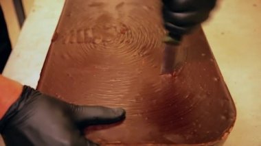 Çikolata fabrikası. Çikolatanın nasıl yapıldığını. Sıcak çikolata musluktan dökülüyor ve tel rafa dökülüyor. Çikolata üretimi yakın plan..