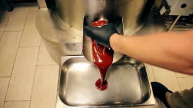 Çikolata fabrikası. Çikolatanın nasıl yapıldığını. Sıcak çikolata musluktan dökülüyor ve tel rafa dökülüyor. Çikolata üretimi yakın plan..