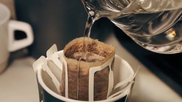 コーヒーを醸造する過程 マグカップの中のドリップコーヒーバッグに水を注ぎます — ストック動画
