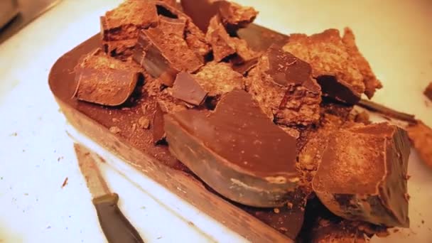 チョコレート工場だ 純粋なチョコレートの冷凍部分 労働者の休憩の手を閉じて ナイフでチョコレートをハンマー チョコレートパン粉 — ストック動画