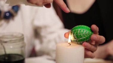 Paskalya yumurtalarını boya ve fırçayla boyayan ellerin yakın çekimi. Boyalı Paskalya yumurtaları. Paskalya için hazırlanırken, el yapımı Paskalya yumurtası yapma işlemini bitirin. Alevler içinde yanan yumurta 