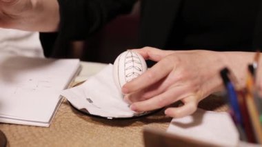 Paskalya yumurtası yapma süreci. Eller ve kalem. Kadın bir yumurtaya eskiz çiziyor, bayrama hazırlanıyor. Geleneksel sanat.