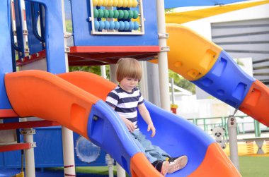 Çocuk dışarıda oyun oynuyordu. Çocuklar anaokulunun bahçesinde oynuyor. Aktif çocuk renkli kayıyor. Komik çocuk renkli kaydırağında eğleniyor. 