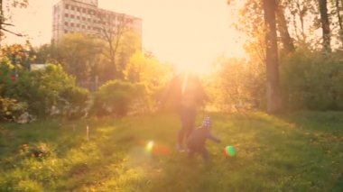 Little boy with blond hair, 2 years old, sitting with his blonde mom on the green grass, eating a banana. Nearby are a toy car and a tractor. Picnic with granny's in the city. sunlight