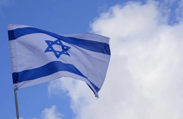 Flag of Israel. Israel flag close up shot on a background of blue sky. White and blue colors. Israel flag waving against clean blue sky