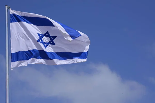 Flag of Israel. Israel flag close up shot on a background of blue sky. White and blue colors. Israel flag waving against clean blue sky