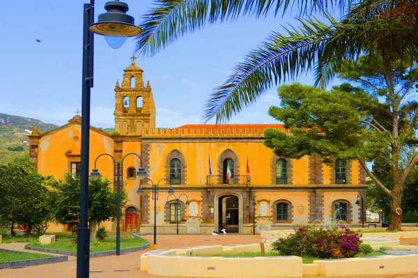 Lipari, Sicilya. Aeolian adası. İtalya. 11 / 10 / 2019 - Belediye binası, devlet memuru. Beyaz gömlekli ve kırmızı kravatlı bir adam beyaz scooter 'a gidiyor. Güzel bina, palmiye dalı