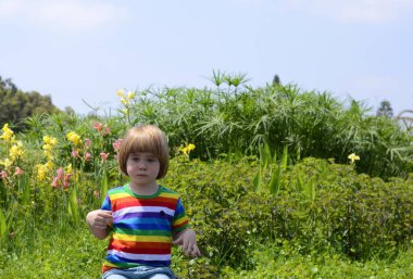A little positive boy in nature, in the garden, by the pond. child in the park