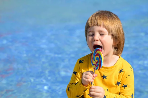 Een Jongetje Eet Een Grote Kleurrijke Lolly Bij Het Zwembad — Stockfoto