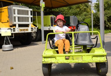 Ramla. İsrail. Haziran 2022. Kamyon ve nakliye müzesi. Küçük bir çocuk bir tren vagonunda oturuyor. Pedallı, itişli bir araba. Çocuklarla seyahat, müzeye gitmek, oğlanlar için eğlence.