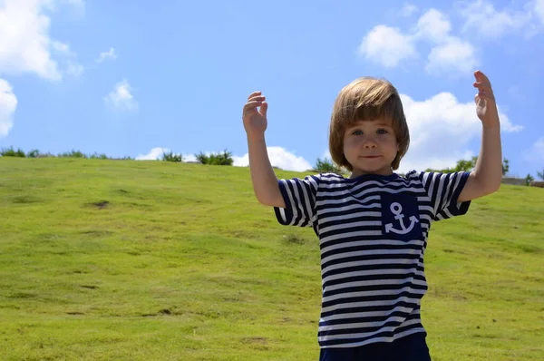 緑の丘と明るい青空に対する海洋ベストの中の小さな男の子の肖像画 テキスト用のスペース コンセプト 海の旅 夏休み 家族の休暇 ヨット 子供のキャンプ — ストック写真
