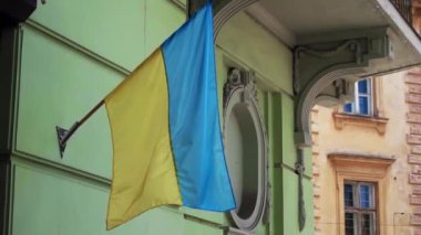 Ukrayna bayrağı eski bir binanın ön cephesinde rüzgârda savruluyor. Sarı-mavi bayrak cesaret ve özgürlüğün sembolüdür Yavaş çekim Lviv Ukrayna