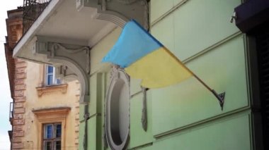 Ukrayna bayrağı eski bir binanın ön cephesinde rüzgârda savruluyor. Sarı-mavi bayrak cesaret ve özgürlüğün sembolüdür Lviv Ukrayna