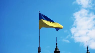 Ukrayna bayrağı rüzgarda, yakın plan. Güzel gökyüzü ve antik şehrin kuleleri. Lviv Yavaş Çekim