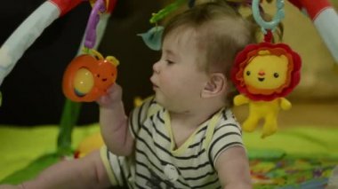 6 aylık, uzun sarı saçlı bir çocuk. Portre. Bir çocuk cep telefonuyla oynar. Yeni doğan dünyayı keşfeder. çocuk oyuncaklara dokunuyor