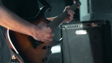 Elektronik solo gitar çalma. Amplifikatörlü bir müzik odası. Kayıt stüdyosunda oturan bir adam gitar seslerini kaydediyor.. 