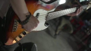 Electric bass Guitar Playing. Guy rock musician plays on stage in a club. Rehearsal for a live performance.