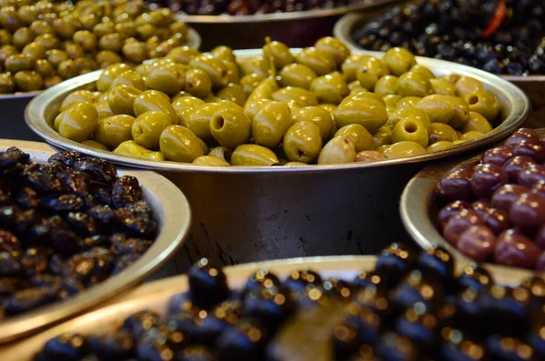 Appetizing olives in assortment. Green and black olives at a market in Tel Aviv. Large beautiful pickled olives.