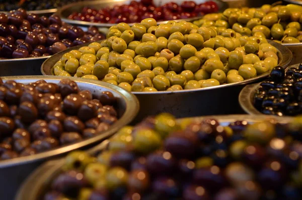 Appetizing olives in assortment. Green and black olives at a market in Tel Aviv. Large beautiful pickled olives.