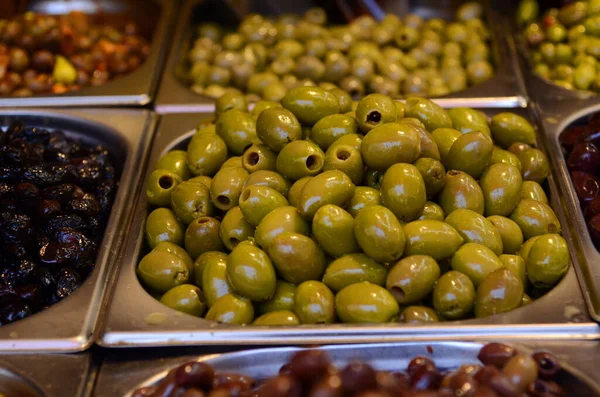 Appetizing olives in assortment. Green and black olives at a market in Tel Aviv. Large beautiful pickled olives.