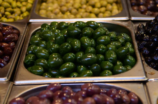 Appetizing olives in assortment. Green and black olives at a market in Tel Aviv. Large beautiful pickled olives.