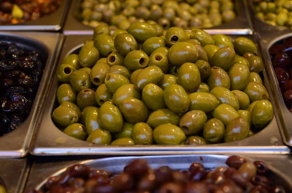 Appetizing olives in assortment. Green and black olives at a market in Tel Aviv. Large beautiful pickled olives.