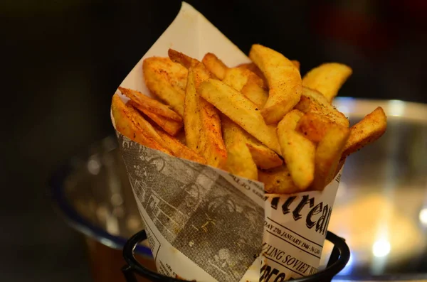 French fries close up. Belgian potatoes in vintage newspaper. Traditional fast food - fried potatoes.
