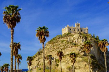Santa Maria dell'Isola Monastery in Tropea. Calabria. Italy. An island in the Tyrrhenian Sea, surrounded by palm trees. White Church on the rock in sea