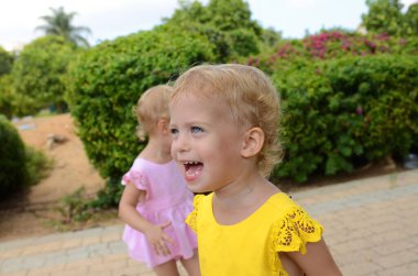 Twin girls. Sisters two years old. Cute positive kids play in the park. The sisters look alike. Family bonds