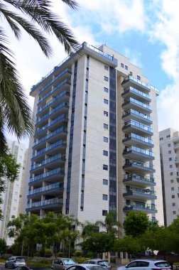 Beautiful residential building surrounded by a garden. Modern housing. Israel - high-rise building, flowering and palm trees. Concept: nice place to live, real estate purchase