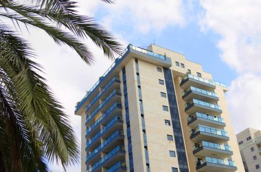 Beautiful residential building surrounded by a garden. Modern housing. Israel - high-rise building, flowering and palm trees. Concept: nice place to live, real estate purchase