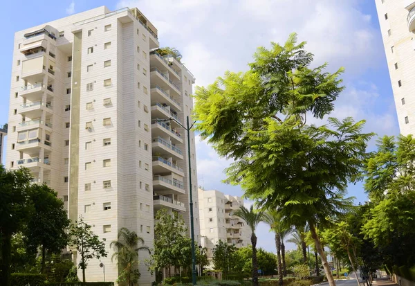 Beautiful residential building surrounded by a garden. Modern housing. Israel - high-rise building, flowering and palm trees. Concept: nice place to live, real estate purchase