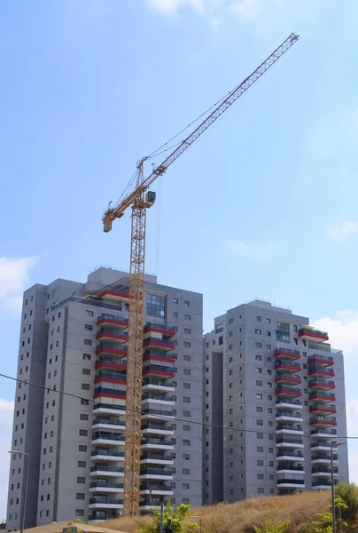Construction of a residential building. Modern architecture. Construction crane and palm tree in the foreground. ISRAEL Rishon LeZion August 2022