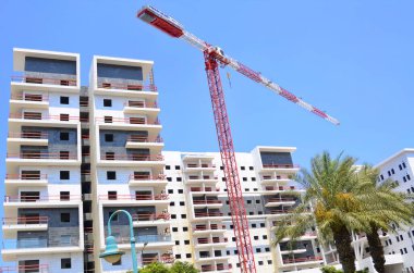 Sunny day, construction site, construction crane. New building in Israel. Concept: real estate agency, apartment on credit, real estate investment. Modern white residential building