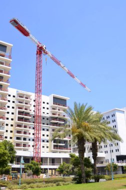 Sunny day, construction site, construction crane. New building in Israel. Concept: real estate agency, apartment on credit, real estate investment. Modern white residential building