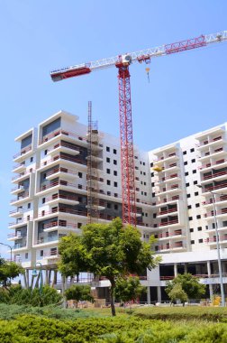 Sunny day, construction site, construction crane. New building in Israel. Concept: real estate agency, apartment on credit, real estate investment. Modern white residential building