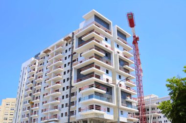 Sunny day, construction site, construction crane. New building in Israel. Concept: real estate agency, apartment on credit, real estate investment. Modern white residential building