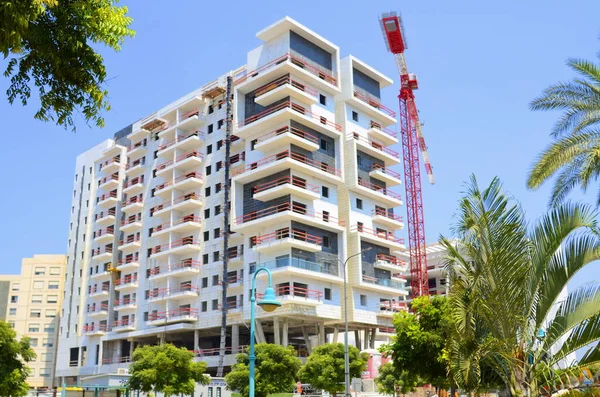 Sunny day, construction site, construction crane. New building in Israel. Concept: real estate agency, apartment on credit, real estate investment. Modern white residential building