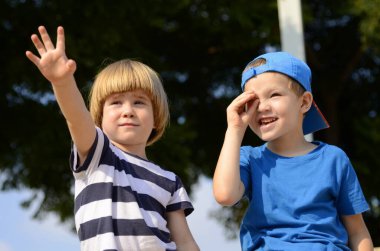 Two little boys, brothers are walking in the park. Children look to the side, point to the object. Concept: Advertising for a kindergarten, school, toy store, amusement park, children's menu.