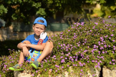 Children with music instruments. Musical education for kids.  Little  boy play music on toy guitar in the park. Cute happy boy smiles in the sun. Summer mood
