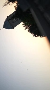 Demir çitin yanında dönen bir kamera. Gün batımında eski taş kilise ve göl manzarası. Sahte çit kapatma videosu