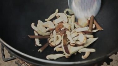 Close up view of sauteed slices of Common Mushrooms (Agaricus bisporus) cooking in the pan WOK. The process of preparing dinner. The chef at work. mushroom farm  fried champignon mushrooms in a pan