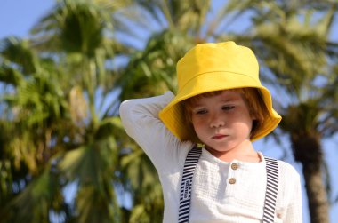 Portrait of a cute boy in a yellow panama hat. A cute child rejoices in the summer. Concept: travel to the resort, holidays with children, kindergarten, holiday, birthday.