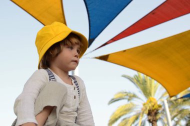 Portrait of a cute boy in a yellow panama hat. A cute child rejoices in the summer. Concept: travel to the resort, holidays with children, kindergarten, holiday, birthday.