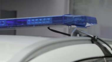 The raindrops reflect blue flashing lights on top of the police car. The roof of a car.Blue warning light on a police car